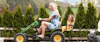 Mutter und Tochter fahren im Familienhotel gemeinsam mit einem Trettraktor über eine kleine Rennstrecke