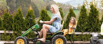 Mutter und Tochter fahren im Familienhotel gemeinsam mit einem Trettraktor über eine kleine Rennstrecke