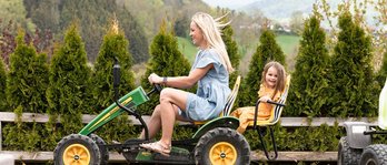 Mutter und Tochter fahren im Familienhotel gemeinsam mit einem Trettraktor über eine kleine Rennstrecke
