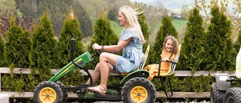 Mutter und Tochter fahren im Familienhotel gemeinsam mit einem Trettraktor über eine kleine Rennstrecke