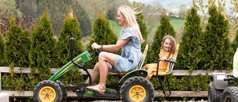 Mutter und Tochter fahren im Familienhotel gemeinsam mit einem Trettraktor über eine kleine Rennstrecke