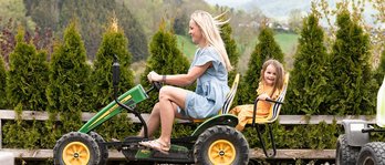 Mutter und Tochter fahren im Familienhotel gemeinsam mit einem Trettraktor über eine kleine Rennstrecke
