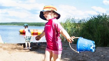 Mädchen spielt mit dem Sand am hoteleigenen Seestrand des Familienhotels Borchard's Rookhus.