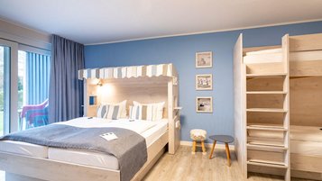 Helles Familienzimmer im Familienhotel Deichkrone mit einem Doppelbett für Eltern im Strandkorb-Look und einem Hochbett für die Kinder.