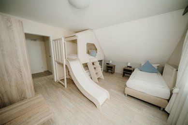 Ein liebevoll eingerichtetes Familienzimmer mit Rutsche macht den Aufenthalt im Familienhotel Friedrichshof unvergesslich.