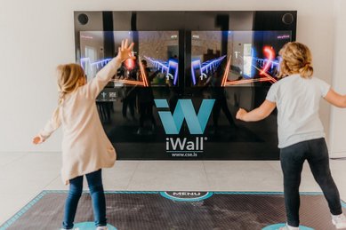 Zwei Kinder tanzen vor der interaktiven Spielwand im Familienhotel Friedrichshof.