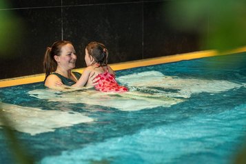 Mutter und Tochter genießen gemeinsam das warme Wasser im Pool des Familienhotels Elldus im Erzgebirge.