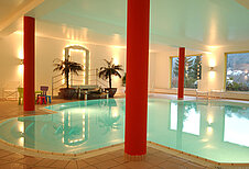 Schwimmbad mit Palmen und Beleuchtung im Familienhotel Mein Krug im Fichtelgebirge.