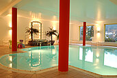 Schwimmbad mit Palmen und Beleuchtung im Familienhotel Mein Krug im Fichtelgebirge.