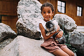 Ein Mädchen hält einen Hasen auf dem Arm im Freilaufgehege im Familienhotel Post Family Resort im Salzburger Land.