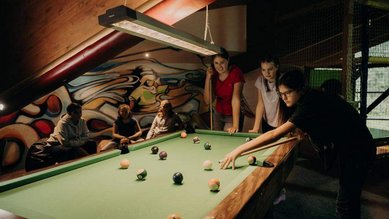 Teens verbringen gemeinsam Zeit beim Billardspielen im Teens-Club des Hotel Sonngastein im Salzburger Land.