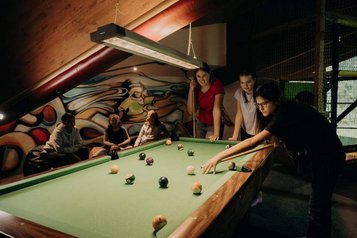 Teens verbringen gemeinsam Zeit beim Billardspielen im Teens-Club des Hotel Sonngastein im Salzburger Land.