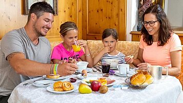 Eine Familie frühstückt im Restaurant im Adler Familien- & Wohlfühlhotel in Tirol.