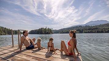 Familie sitzt am Steg des Reintalersees in Tirol und genießt die Sonne.