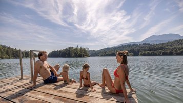 Familie sitzt am Steg des Reintalersees in Tirol und genießt die Sonne.