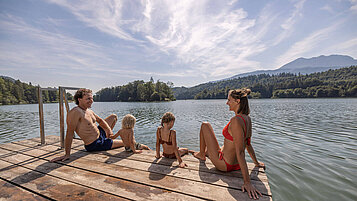 Familie sitzt am Steg des Reintalersees in Tirol und genießt die Sonne.