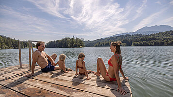 Familie sitzt am Steg des Reintalersees in Tirol und genießt die Sonne.