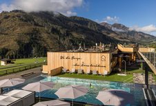 Außenpool mit Sonnenliegen und Panoramablick auf die Berge im Familienhotel Almfamilyhotel Scherer in Osttirol.
