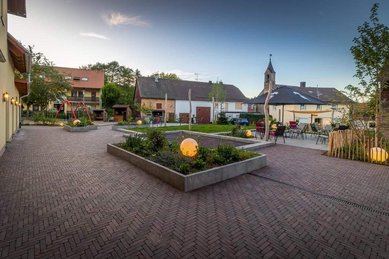 Innenhof im Familienhotel Ottonenhof im Sauerland mit Blumenbeeten, Sitzbereichen und Kirche im Hintergrund.