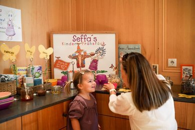 Kind freut sich am bunt gestalteten Kinderfrühstücksbuffet im Familienhotel Sonne Bezau.