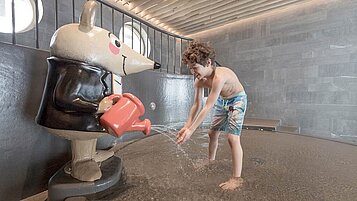 Zwei Kinder planschen fröhlich im Schwimmbecken des Hallenbads im Familienhotel Gorfion in Liechtenstein.