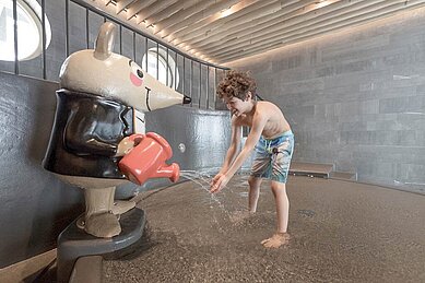 Zwei Kinder planschen fröhlich im Schwimmbecken des Hallenbads im Familienhotel Gorfion in Liechtenstein.