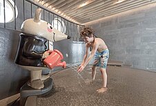 Zwei Kinder planschen fröhlich im Schwimmbecken des Hallenbads im Familienhotel Gorfion in Liechtenstein.