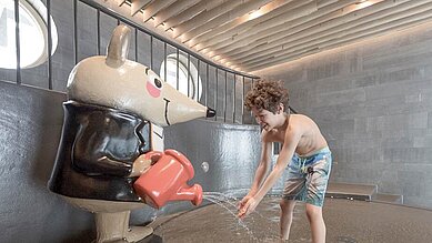 Zwei Kinder planschen fröhlich im Schwimmbecken des Hallenbads im Familienhotel Gorfion in Liechtenstein.