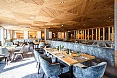 Restaurant mit großen Tischen und gemütlichen Sesseln im modernen Stil im Familienhotel Das Bayrischzell in Oberbayern.