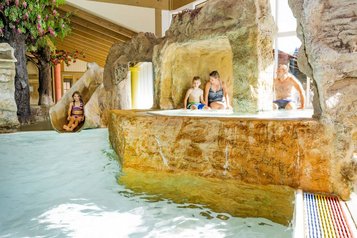 Familie entdeckt die Wasserwelt mit Rutsche und Felsengrotte im Familienhotel Krone im Allgäu.