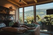 Raum für Wellnessbehandlungen im Familienhotel Mia Alpina in Tirol mit Behandlungsliegen, großen Fenstern und Bergblick.