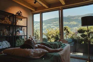 Raum für Wellnessbehandlungen im Familienhotel Mia Alpina in Tirol mit Behandlungsliegen, großen Fenstern und Bergblick.