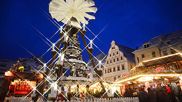 Erlebt eine einmalige Weihnachtsstimmung auf dem Weihnachtsmarkt in Freiburg. Auf dem Marktplatz steht ein große Weihnachtspyramide.