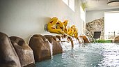 Kinderbecken im Hotel mit wasserspeienden Clownfisch-Figuren an der Wand, die in ein warmes, sprudelndes Becken münden, für eine spielerische und kinderfreundliche Badeerfahrung.