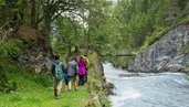 Familie wandert neben einem Bach in der Nähe vom Familienhotel Bella Vista in Südtirol.
