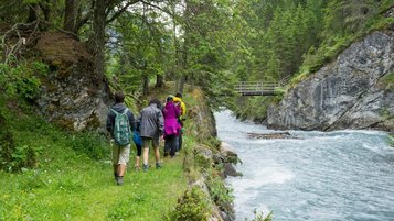 Familie wandert neben einem Bach in der Nähe vom Familienhotel Bella Vista in Südtirol.