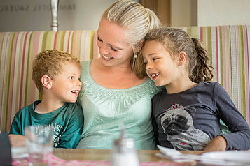 Mutter mit ihren zwei Kindern am Tisch im Familienhotel Ottonenhof im Sauerland.