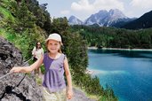 Ein Mädchen wandert mit ihrer Mutter auf einem schmalen Pfad oberhalb eines türkisblauen Sees in den Bergen nahe dem Familienhotel Tirolerhof.