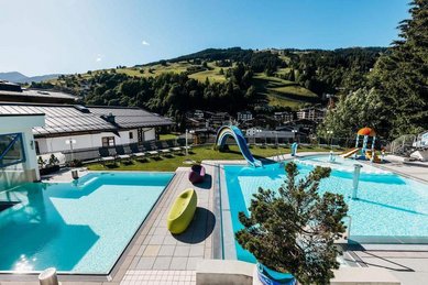 Outdoor-Pool mit Wasserrutsche und Blick auf die Berge im Wellness- & Familienhotel Egger im Salzburger Land.