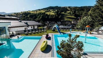 Outdoor-Pool mit Wasserrutsche und Blick auf die Berge im Wellness- & Familienhotel Egger im Salzburger Land.