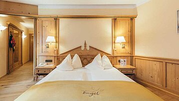 Gemütliches Doppelbett in einer 2-Raum Suite im Familienhotel Engel Gourmet & Spa in Südtirol.