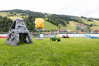 Große Spielwiese mit Kletterstein, Tracktoren und Fußballtor im Wellness- & Familienhotel Egger in Saalbach Hinterglemm.