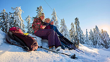 Eine Gruppe Winterwanderer macht eine Pause in der Nähe von Sankt Englmar im Bayerischen Wald im Schnee.