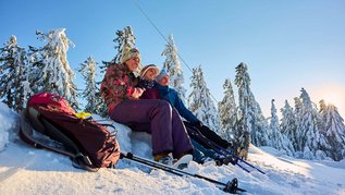 Eine Gruppe Winterwanderer macht eine Pause in der Nähe von Sankt Englmar im Bayerischen Wald im Schnee.