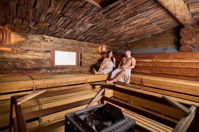Paar entspannt in der gemütlichen Holzsauna im Familienhotel Feldberger Hof im Schwarzwald.