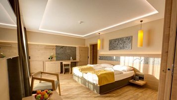 Modernes Familienzimmer mit Doppelbett, Holzmöbeln und warmem Licht im Familienhotel Aigo.