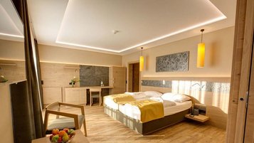 Modernes Familienzimmer mit Doppelbett, Holzmöbeln und warmem Licht im Familienhotel Aigo.