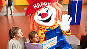Das Familotel-Maskottchen Happy liest Kindern eine Geschichte vor
