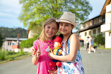 Zwei glückliche Mädchen auf dem Hotelgelände des Familienhotels Mein Krug im Fichtelgebirge im Sommer bei schönem Wetter.